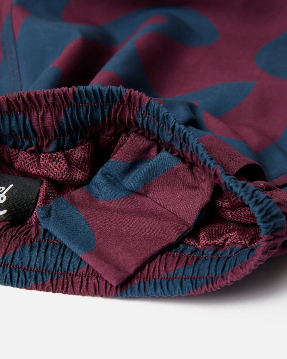 Detail of the elastic waistband and mesh lining on burgundy ByParra Splashed Swim Shorts.
