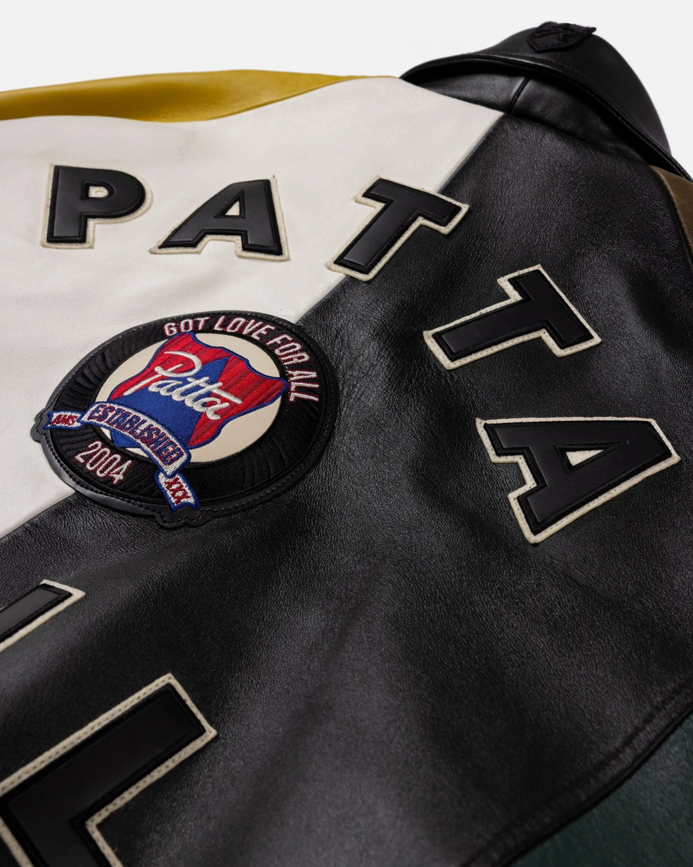 Detail of embroidered crest patch and leather lettering on the back of the Patta x Avirex Icon Jacket.
